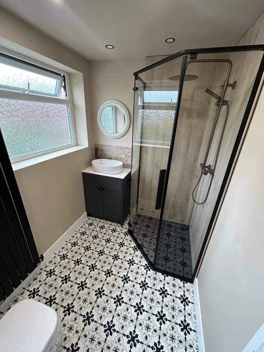 Shower room with patterned floor tiles and black framed enclosure