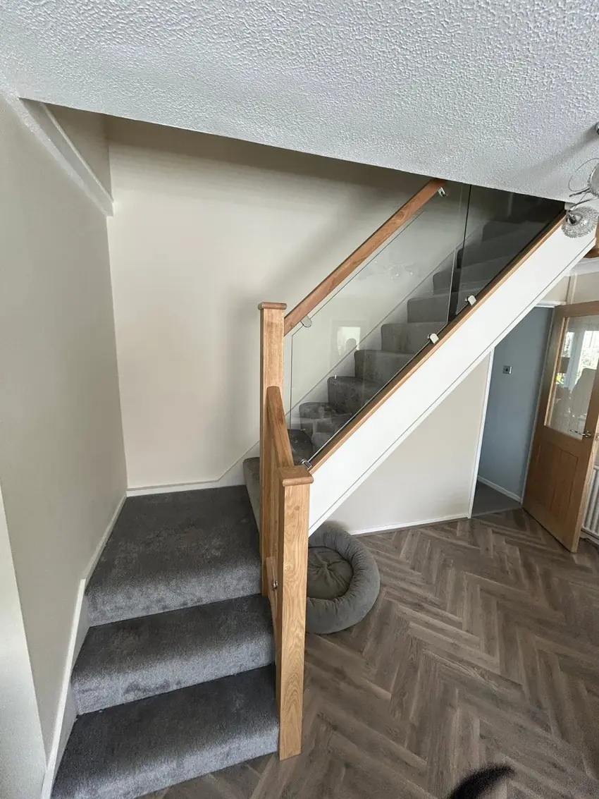 Oak and glass staircase balustrade with herringbone hallway flooring
